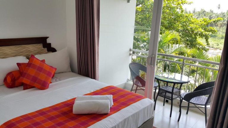 Habitación doble con cama matrimonial y balcón con vistas a jardín tropical en Hotel Elephant Park