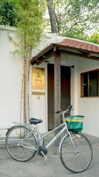Entrada principal de The Pavilion con bicicleta estacionada y jardín de bambú