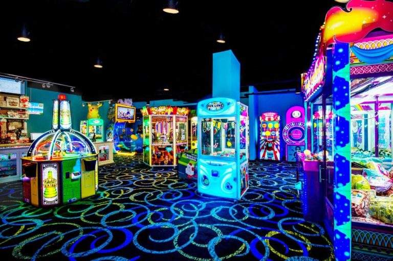 Sala de juegos arcade con máquinas de premios y luces de neón en The Grove Resort Orlando