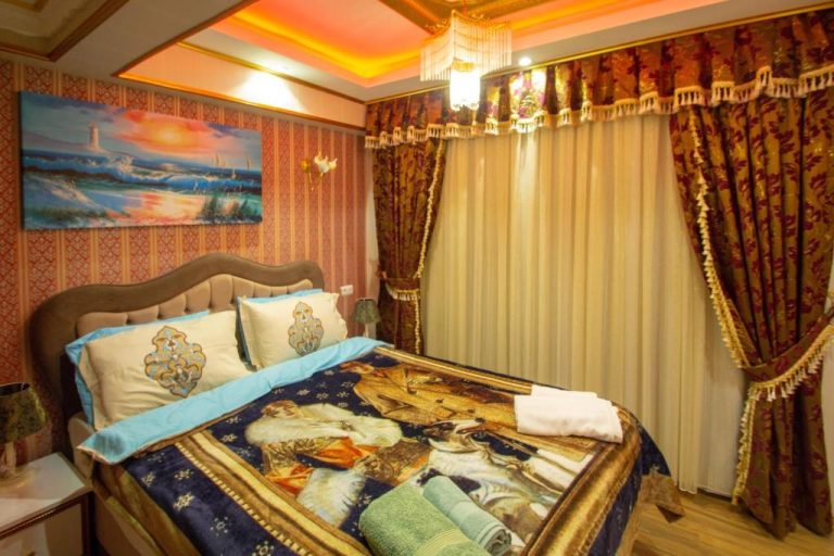 Habitación doble de lujo con cama decorada y cortinas ornamentales en Hotel Marko Pasa Konagi