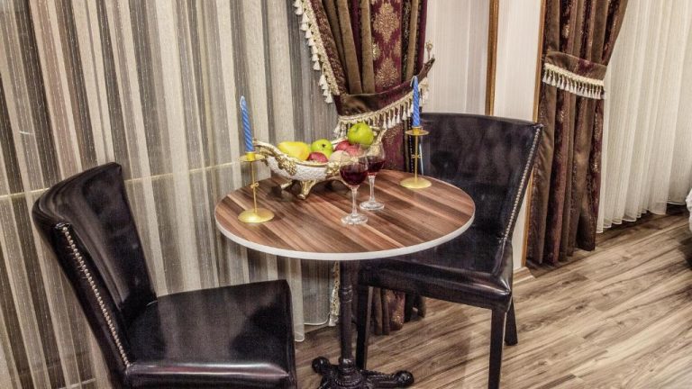 Mesa redonda con copas de vino y frutas frescas en el Hotel Marko Pasa Konagi con decoración clásica