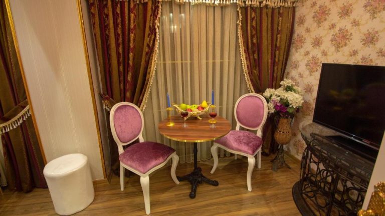Rincón romántico con mesa redonda y sillas tapizadas en rosa del Hotel Marko Pasa Konagi