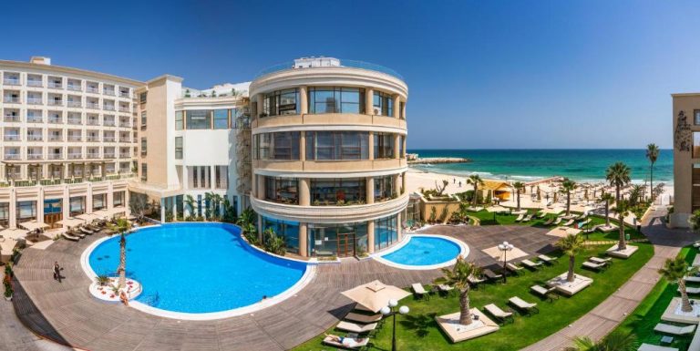 Piscina exterior con tumbonas y vistas al mar del Sousse Palace Hotel & Spa en Túnez