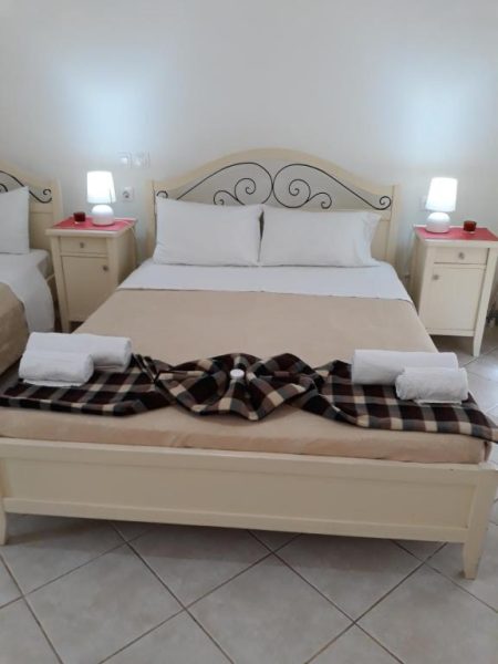 Habitación doble con cama matrimonial y mesitas de noche iluminadas en Pulades Resort