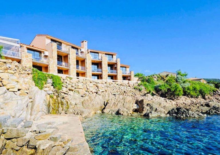 Fachada del Hôtel du Golfe con vistas al mar cristalino y terraza sobre rocas en la costa