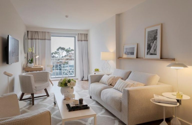 Salón elegante con sofá gris y vistas al mar desde el balcón en Hotel Bellevue Dubrovnik