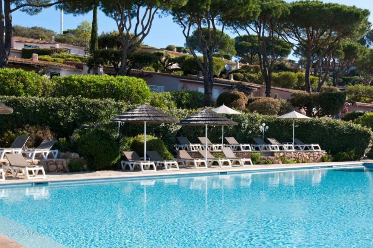 Piscina exterior con tumbonas y sombrillas de paja en Résidence Marina Di Santa Giulia, Córcega