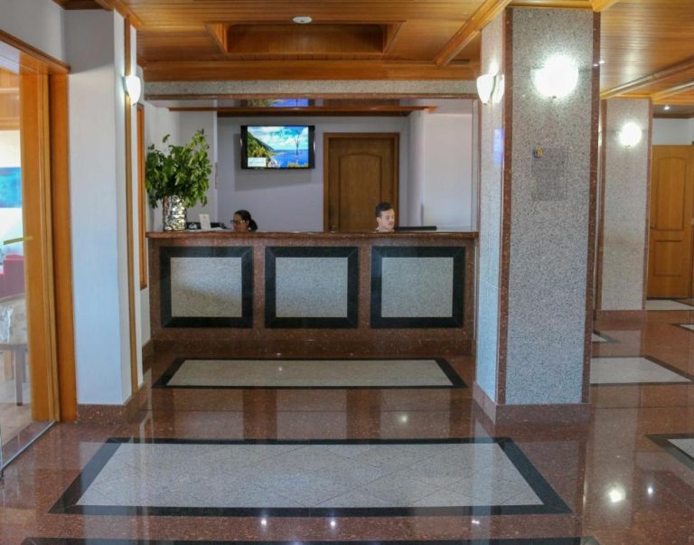 Recepción principal del Hotel Horta con suelo de mármol y mostrador de granito con personal atendiendo