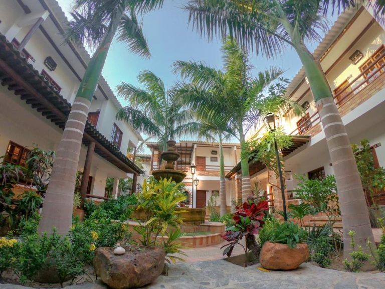 Patio interior con palmeras tropicales y fuente decorativa del Camali Hotel rodeado de jardines