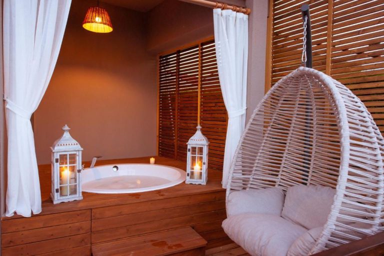 Jacuzzi romántico con velas y silla colgante de mimbre en terraza del Arwen Hotel