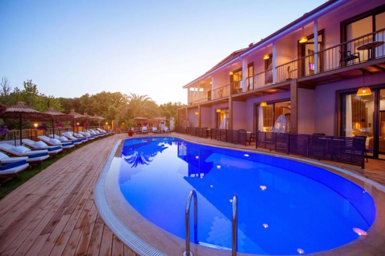 Piscina exterior iluminada con terraza de madera y tumbonas del Arwen Hotel al atardecer