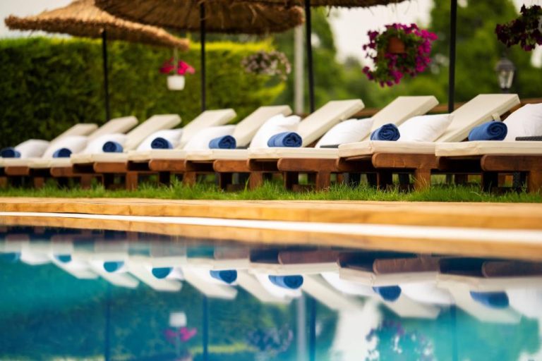 Tumbonas con toallas azules junto a la piscina exterior del Arwen Hotel rodeada de vegetación