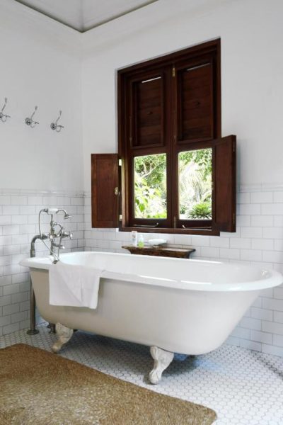 Baño de lujo con bañera exenta vintage y ventana de madera en Round Hill Hotel & Villas Jamaica