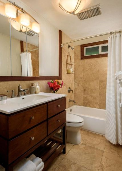 Baño completo con bañera, ducha y tocador de madera en el Paia Inn, Hawaii