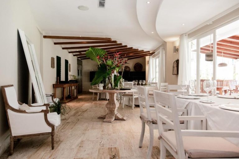 Restaurante interior del Sublime Samaná con mesas blancas, vigas de madera y decoración tropical