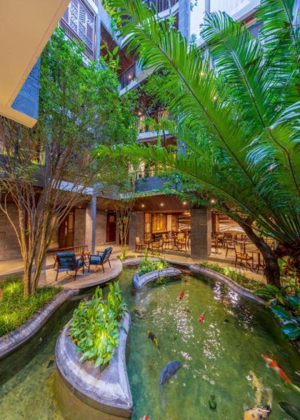 Jardín interior con estanque de peces koi y vegetación tropical en el Minh Boutique Hotel