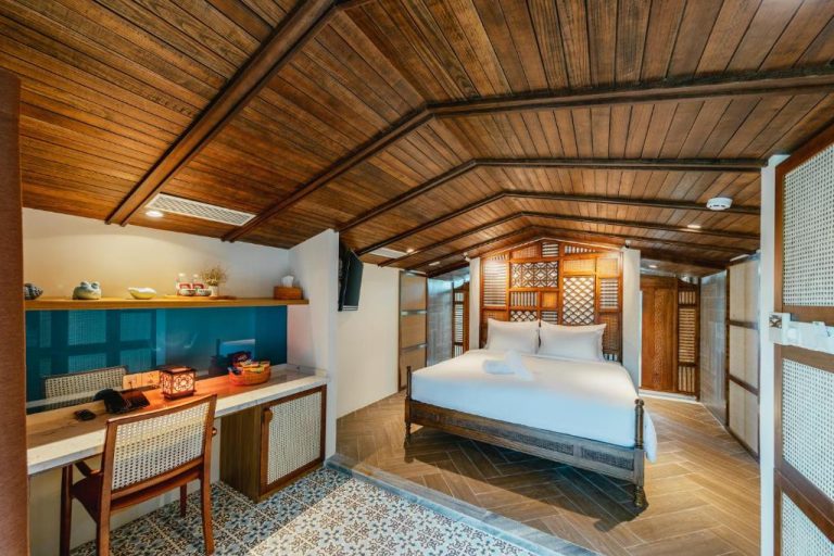Habitación con techo de madera y cama dorada en el Minh Boutique Hotel, estilo colonial vietnamita
