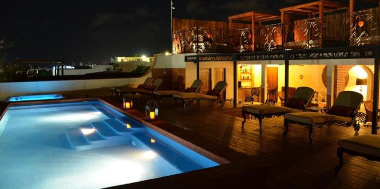 Piscina iluminada en terraza nocturna del La Pasion Colonial Hotel Boutique By Bunik con área de descanso
