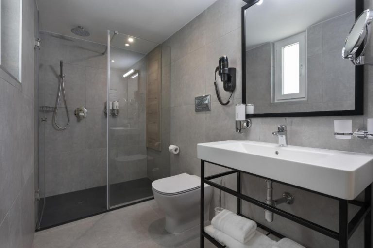 Baño moderno con ducha de lluvia y lavabo suspendido en el Azur Hotel by ST Hotels
