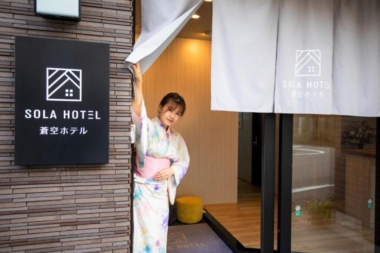 Mujer con yukata tradicional japonés en la entrada principal del Sola Hotel en Japón