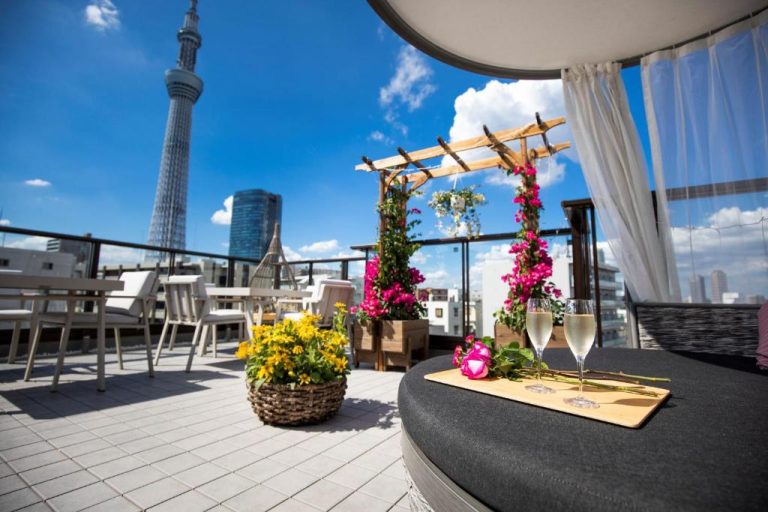 Terraza exterior del Sola Hotel con vistas a la Tokyo Skytree y copas de champán entre flores