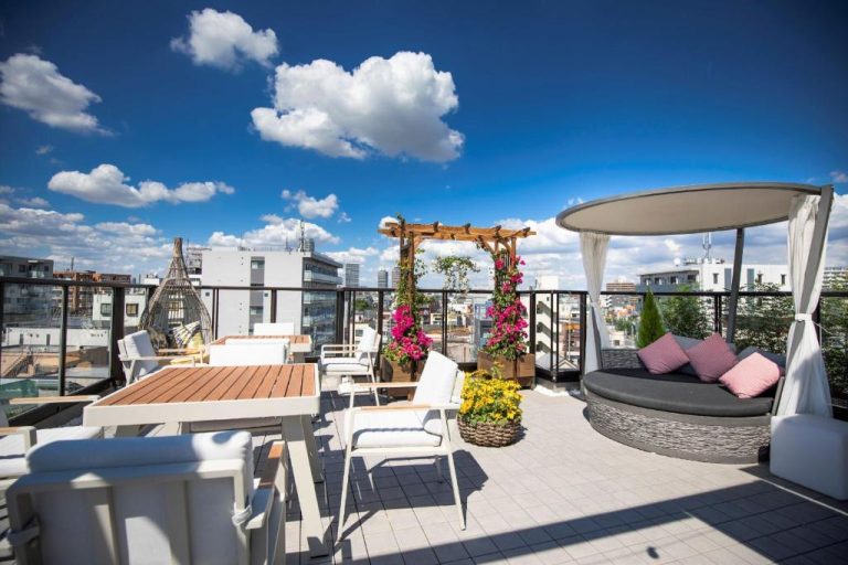 Terraza lounge en la azotea del Sola Hotel con tumbonas, pérgola floral y vistas panorámicas de la ciudad