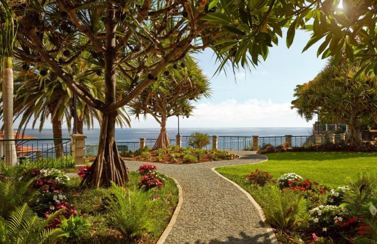 Jardín tropical con camino de piedra y vistas al mar en The Cliff Bay PortoBay Madeira