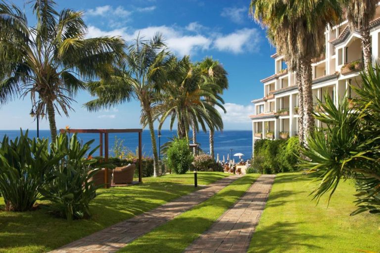 Jardines tropicales con palmeras y vistas al mar del hotel The Cliff Bay PortoBay en Madeira