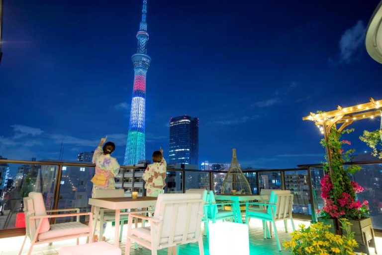 Terraza del Sola Hotel con vistas nocturnas a la Tokyo Skytree iluminada y dos huéspedes en yukata