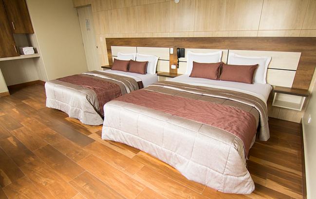 Habitación doble con dos camas y suelo de madera en Hotel Martinika, decoración moderna en tonos beige y granate