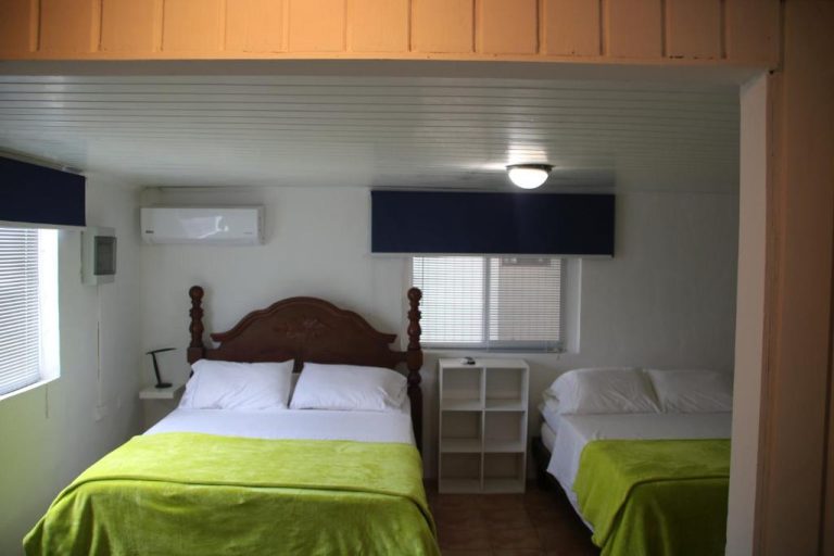 Habitación doble con dos camas y ropa de cama verde en el Coral Reef Beach Hotel