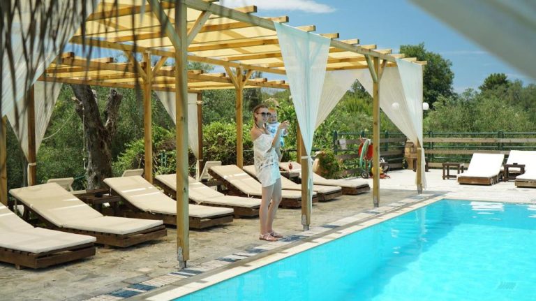 Piscina exterior con tumbonas y pérgola de madera en Spiti Nikos, ideal para el relax en verano