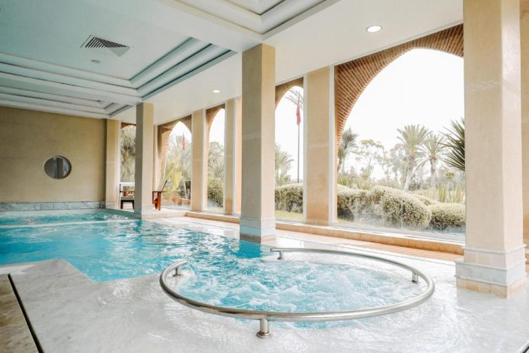 Piscina interior con jacuzzi y arcos andaluces del Tikida Golf Palace con vistas al jardín