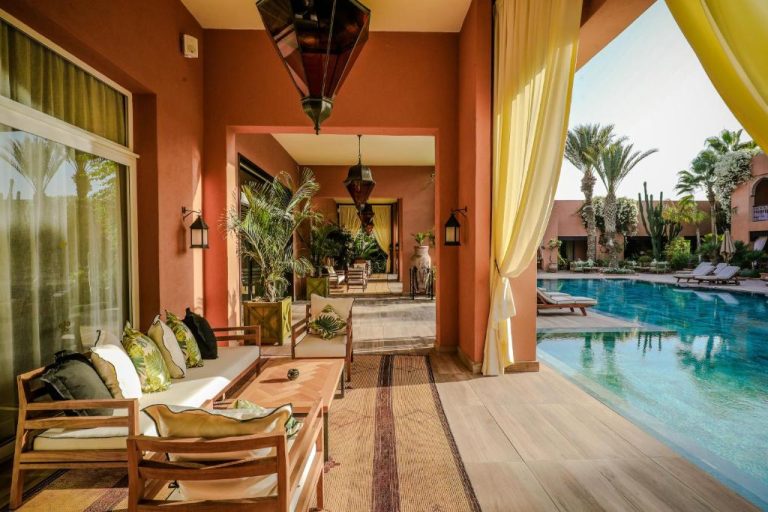 Terraza con sofás y lámparas árabes junto a la piscina exterior del Tikida Golf Palace en Marrakech