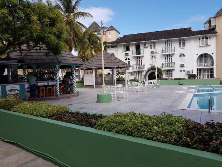 Piscina exterior con bar de piscina y gazebo del hotel Almond Grove at Sand Castle en Jamaica