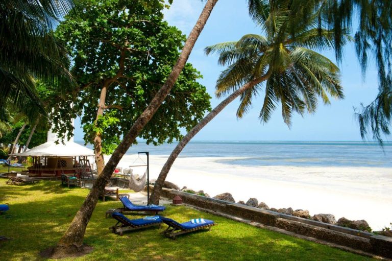 Tumbonas junto a la playa de arena blanca con palmeras tropicales en Severin Sea Lodge Kenia