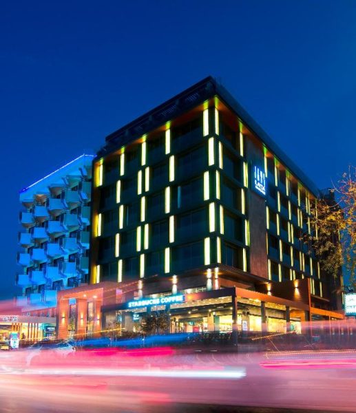 Fachada nocturna iluminada del Ilayda Avantgarde Hotel con Starbucks en planta baja