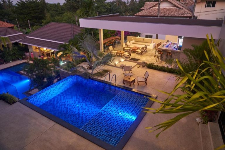 Piscina iluminada de noche con zona lounge y bar exterior en Baan Sawan Samui Resort