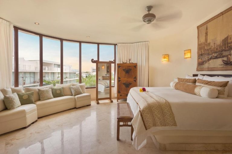 Suite amplia con cama king y sofá en Porto Playa Condo Hotel and Beach Club con vistas al exterior