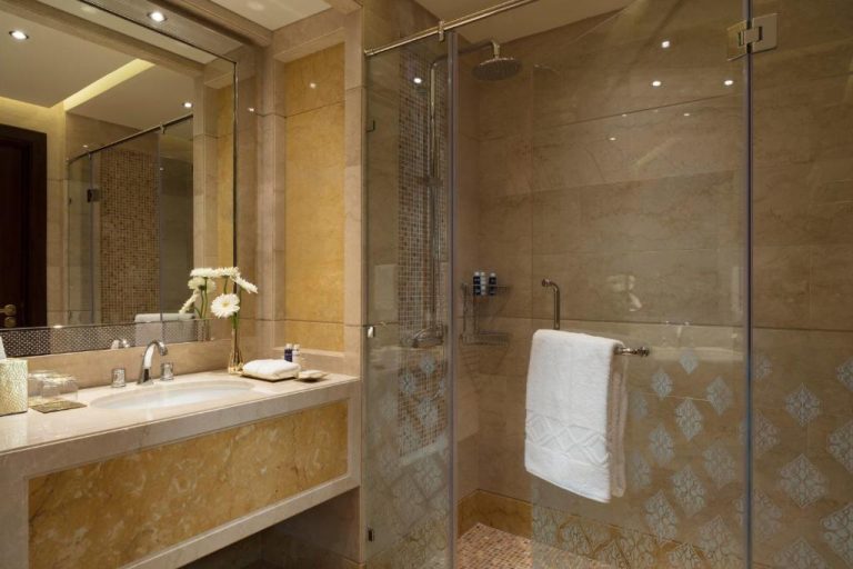 Baño de lujo con ducha de lluvia y revestimiento de mármol en Al Najada Doha Hotel Apartments by Oaks