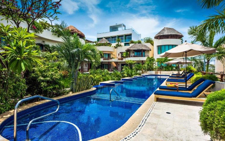 Piscina exterior con tumbonas y jardín tropical del Porto Playa Condo Hotel and Beach Club