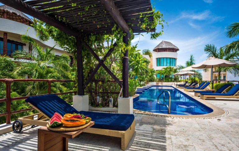 Piscina exterior con tumbonas azules y frutas tropicales en Porto Playa Condo Hotel and Beach Club
