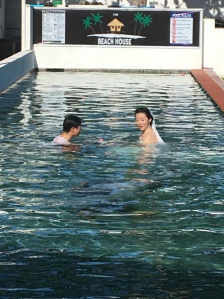 Pareja disfrutando de la piscina exterior de The Beachhouse Cebu con aguas cristalinas