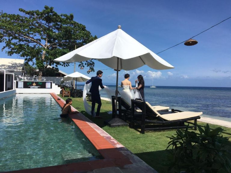 Pareja celebrando una boda junto a la piscina exterior con vistas al mar en The Beachhouse Cebu