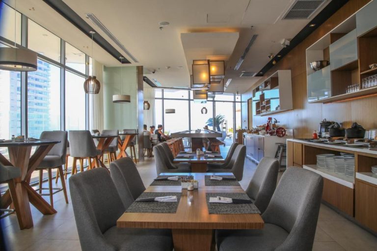 Restaurante moderno con mesas y sillas grises del Grand Marina Suites Santa Marta con vistas panorámicas