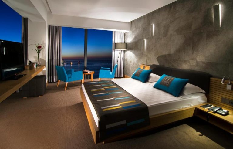 Habitación de lujo con cama doble y vistas panorámicas al mar al atardecer en Ilayda Avantgarde Hotel