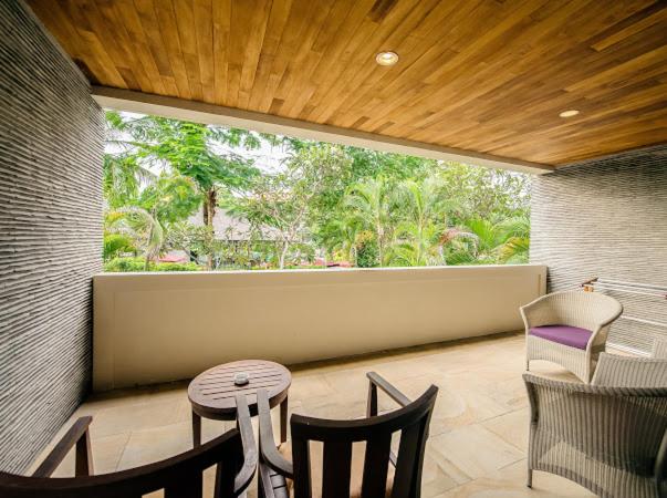 Terraza cubierta con vistas al jardín tropical del Ruby Nusa Dua Bali con mesa y sillas