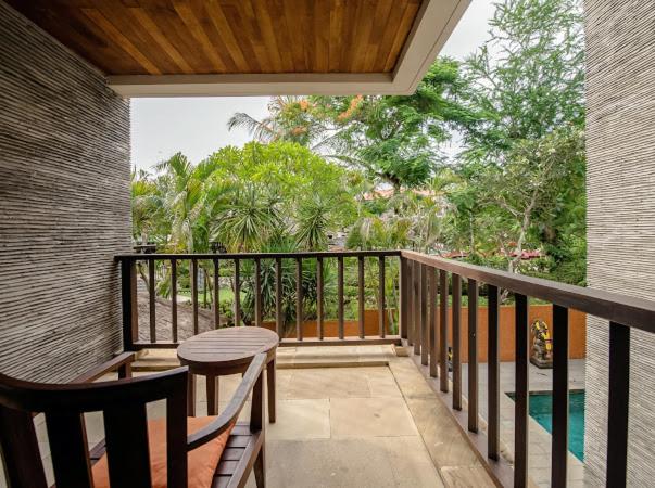 Terraza privada con sillas de madera y vista al jardín tropical en el Ruby Nusa Dua Bali