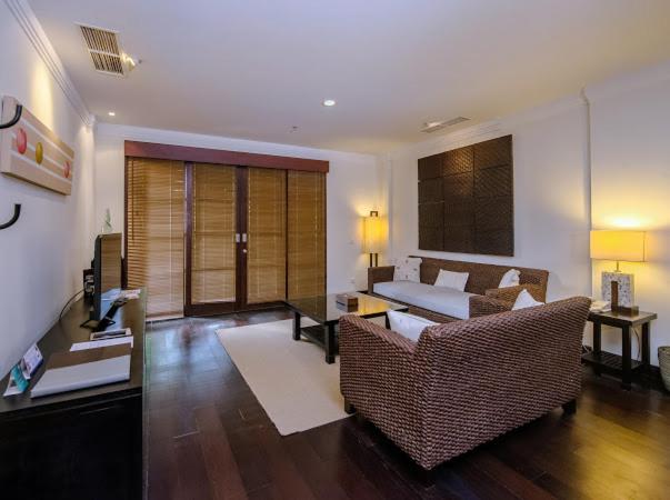 Salón de suite con sofás de ratán y suelos de madera oscura en el Hotel Ruby Nusa Dua Bali