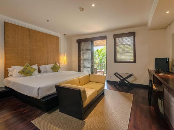 Habitación superior con cama doble, sofá y terraza con vistas tropicales en Ruby Nusa Dua Bali